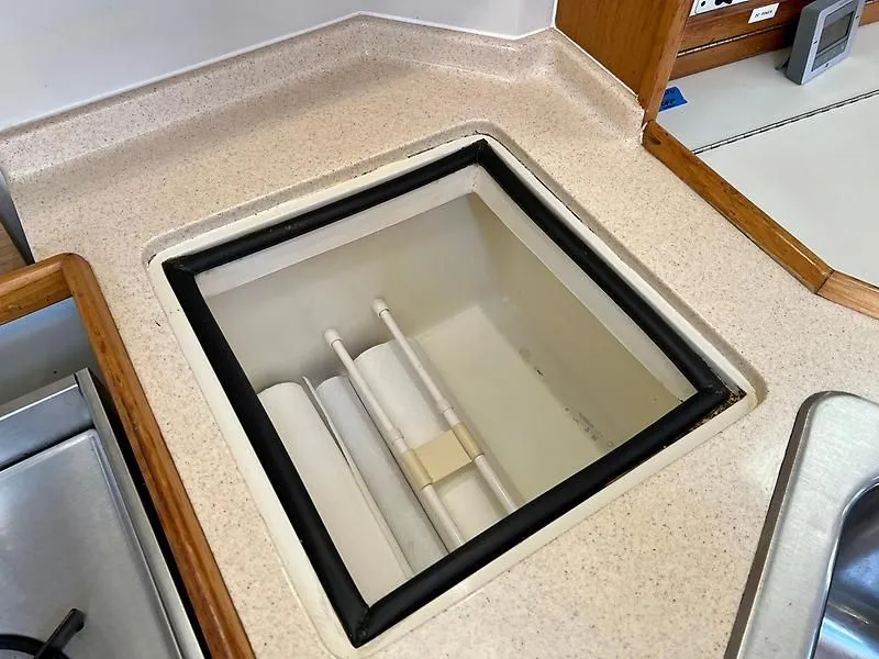 Slide: The Image of Catalina 320 (2000) boat interior storage compartment with beige countertop and wooden trim. - 37