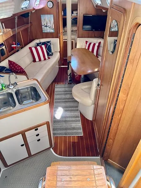 Slide: The Image of Interior of 2000 Catalina 320 sailboat with cozy seating, wooden finishes, and compact kitchen area. - 47