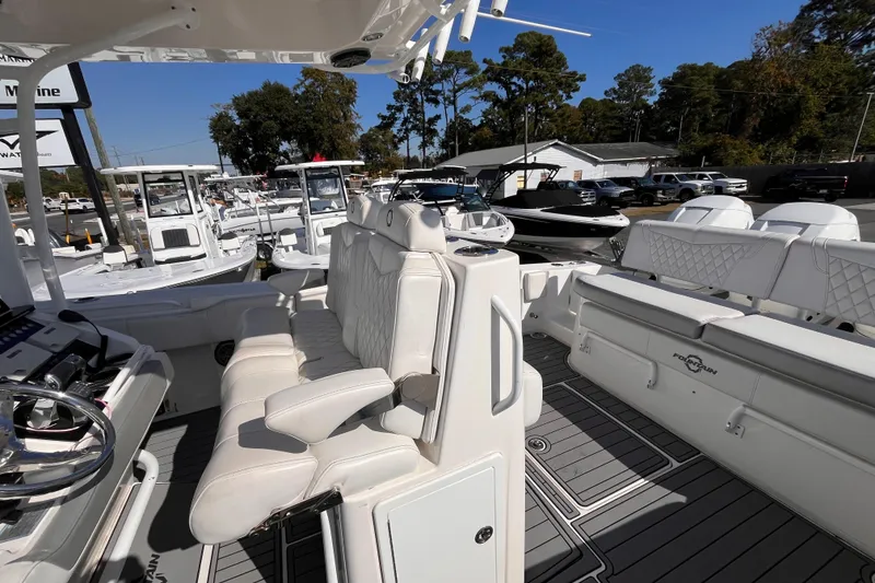 Slide: The Image of 2019 Fountain 38 Center Console boat with white seating and modern dashboard, docked outdoors. - 18
