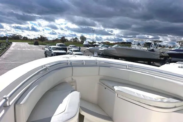 Slide: The Image of 2020 Cobia 237 Center Console boat with cushioned seating, parked near other vehicles. - 4