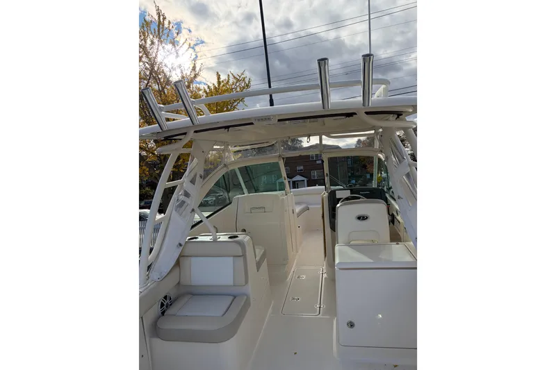 Slide: The Image of 2012 Pursuit DC 265 Dual Console boat interior with seating and helm, under cloudy sky. - 6