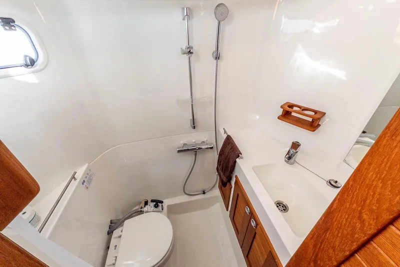 Slide: The Image of 2023 Targa 27.2 boat bathroom with shower, sink, and wooden accents. - 33