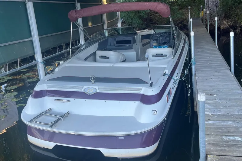 Slide: The Image of 1995 Cobalt 252 boat docked, featuring maroon and white design, with canopy and seating. - 5