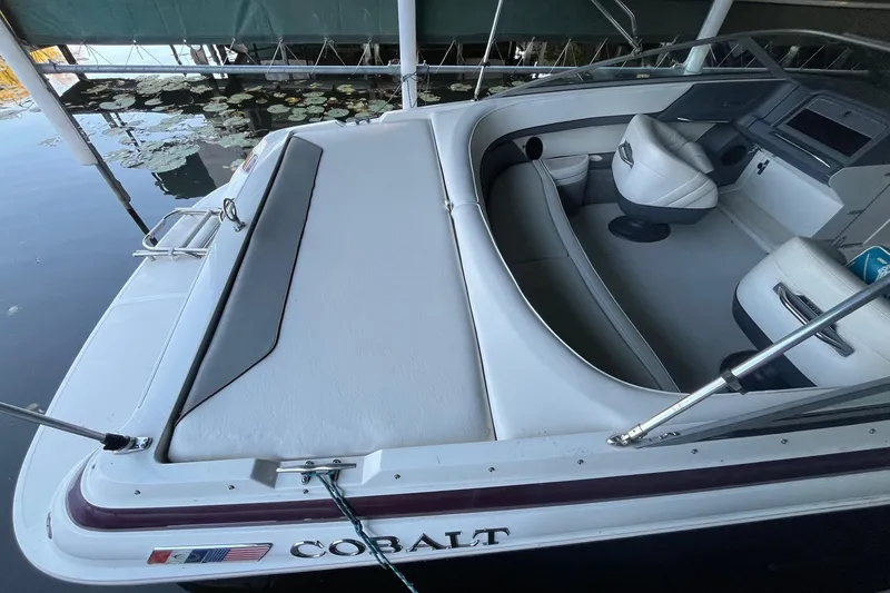 Slide: The Image of 1995 Cobalt 252 boat interior with white seating and dashboard, docked near water lilies. - 6