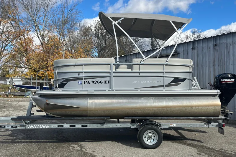 The Image of 2024 Starcraft LX 16 R pontoon boat on trailer, with Mercury outboard motor. - 0