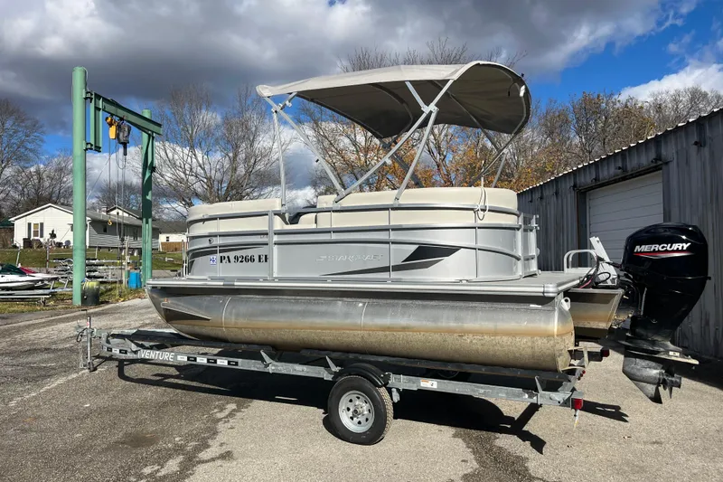 Slide: The Image of 2024 Starcraft LX 16 R pontoon boat on trailer, featuring Mercury outboard motor. - 10