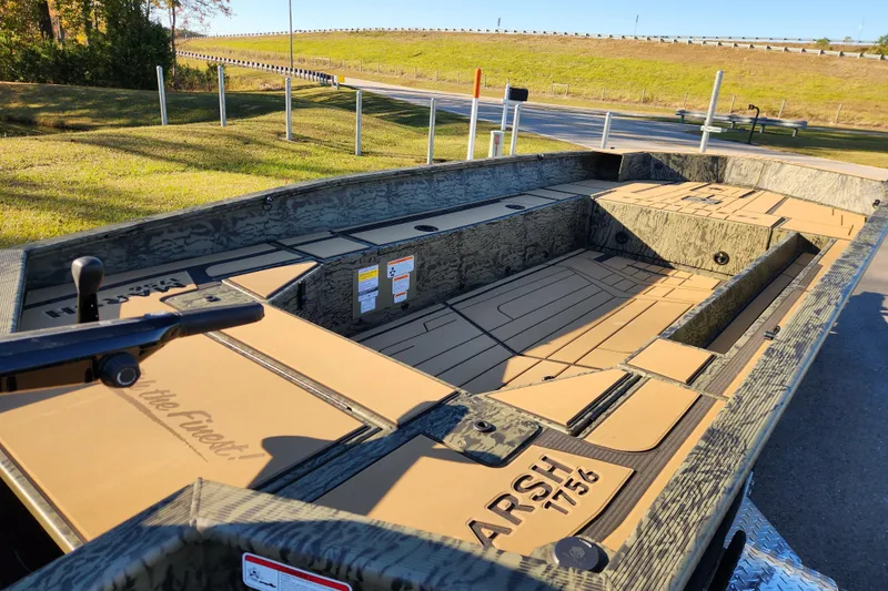 Slide: The Image of 2026 Tracker Grizzly 1756 T Marsh boat with camo design, parked outdoors. - 12