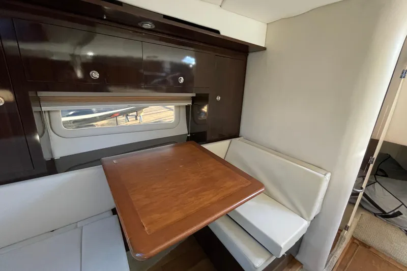 Slide: The Image of Interior of 2016 Sea Ray 310 Sundancer with wooden table and white seating. - 2