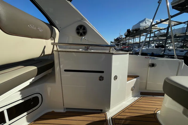 Slide: The Image of 2016 Sea Ray 310 Sundancer interior with seating and kitchenette, docked at marina. - 21