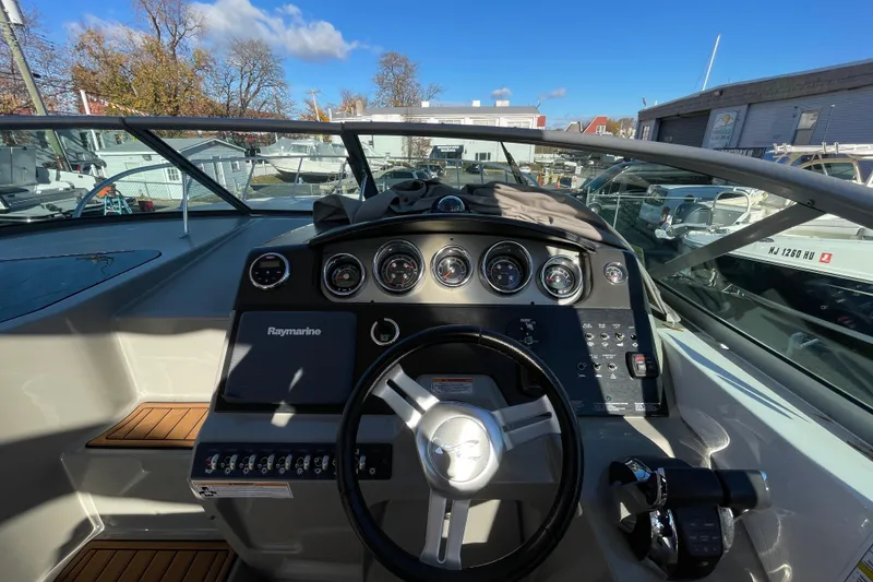 Slide: The Image of 2016 Sea Ray 310 Sundancer dashboard with steering wheel and gauges under clear blue sky. - 22