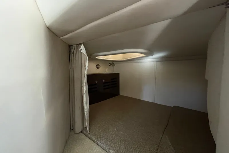 Slide: The Image of 2016 Sea Ray 310 Sundancer cabin interior with cozy sleeping area and curtain. - 7