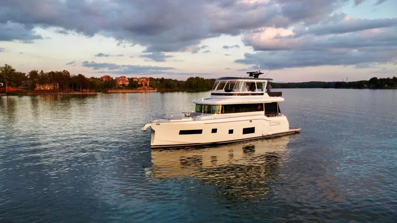 Slide: The Image of 2021 Sirena 58 yacht cruising on a serene lake at sunset. - 2