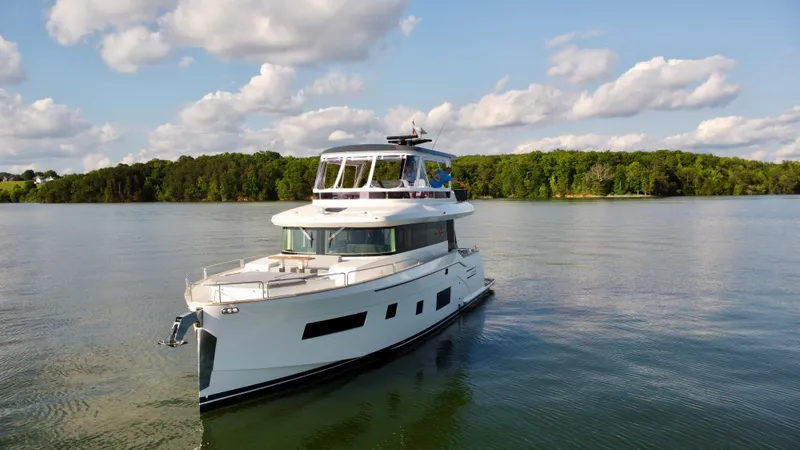 Slide: The Image of 2021 Sirena 58 yacht cruising on a serene lake under a partly cloudy sky. - 6