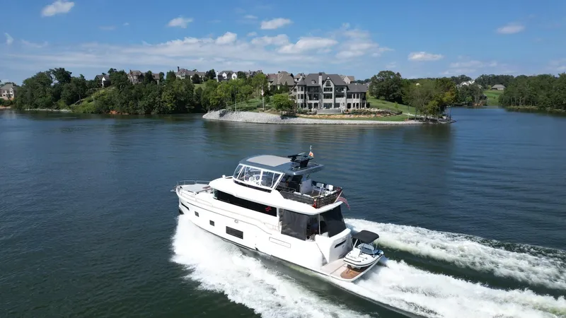 Slide: The Image of 2021 Sirena 58 yacht cruising on a scenic lake near luxury homes. - 9