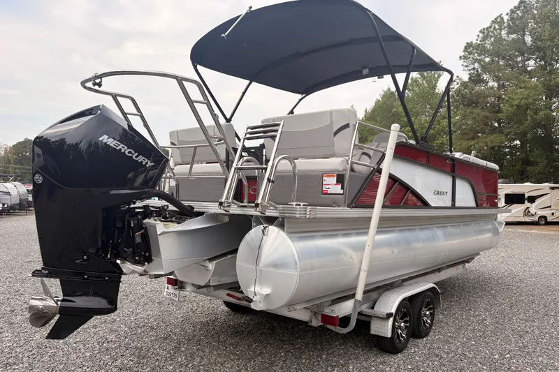 Slide: The Image of 2023 Crest Classic LX 220 SLRC pontoon boat with Mercury engine, parked on a trailer. - 23