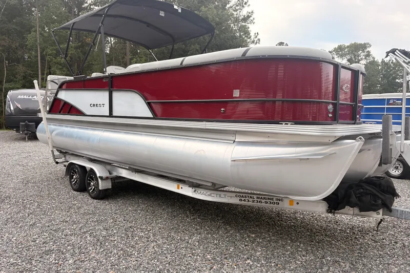 Slide: The Image of 2023 Crest Classic LX 220 SLRC pontoon boat on trailer, red and silver design. - 4