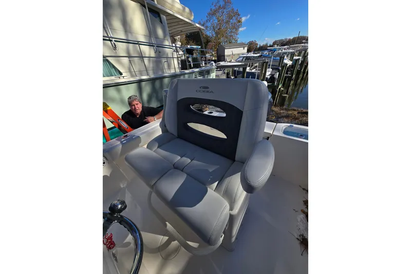 Slide: The Image of 2020 Cobia 220 Center Console boat with cushioned seating at a marina. - 21