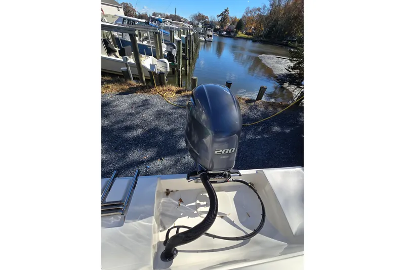 Slide: The Image of 2020 Cobia 220 Center Console boat with 200 horsepower outboard motor by a dock. - 25