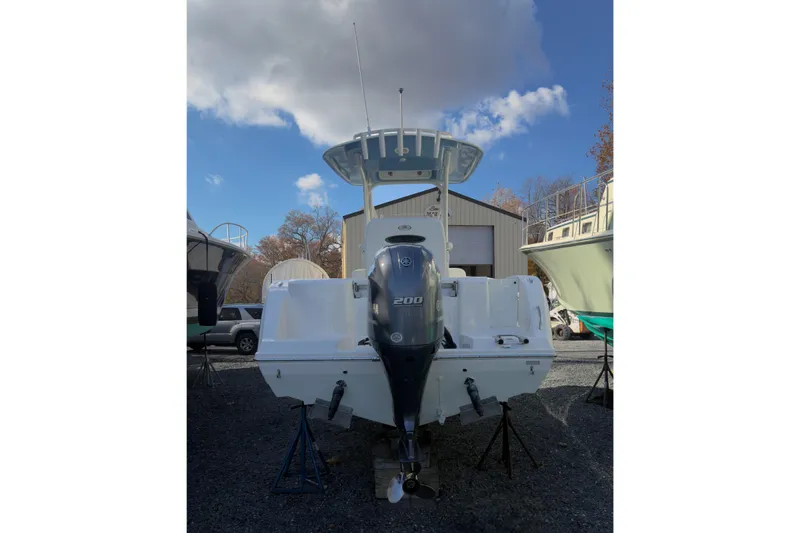 Slide: The Image of 2020 Cobia 220 Center Console boat with white seating, docked near a storage facility. - 3