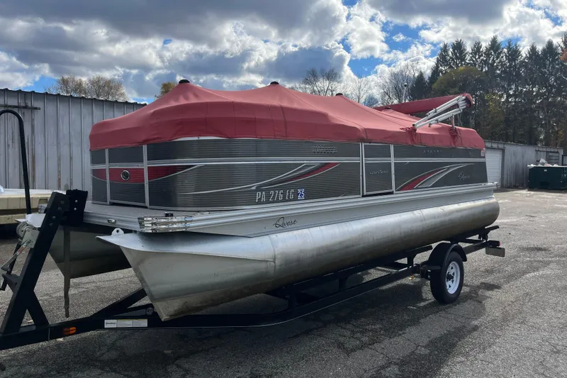 Slide: The Image of 2020 Apex Avanti 820 pontoon boat with red cover on a trailer, parked outdoors. - 11