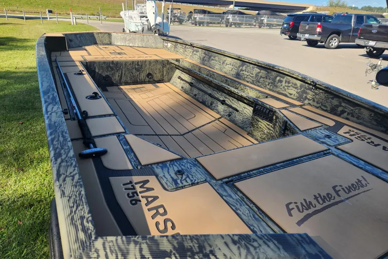 Slide: The Image of 2026 Tracker Grizzly 1756 T Marsh boat with camo design, parked outdoors. - 11
