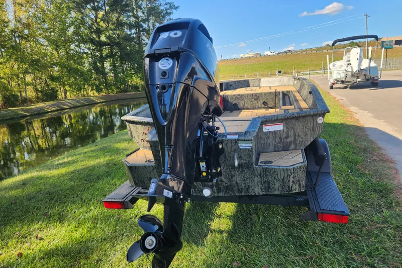 Slide: The Image of 2026 Tracker Grizzly 1756 T Marsh boat with outboard motor on grassy area near water. - 3