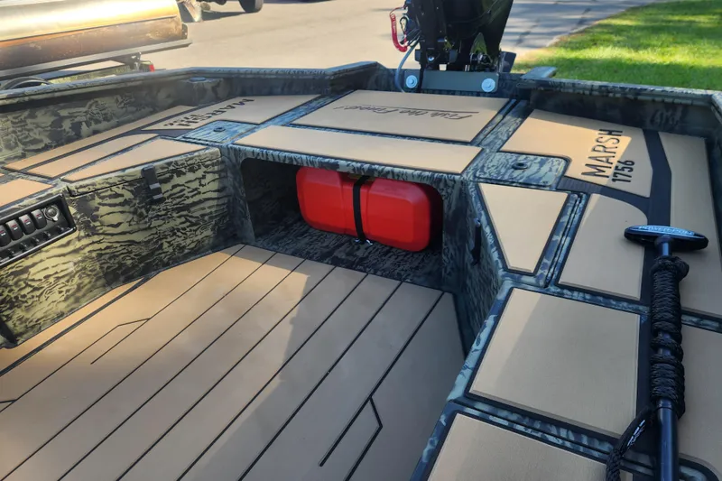 Slide: The Image of 2026 Tracker Grizzly 1756 T Marsh boat interior with camouflage design and red fuel tank. - 8