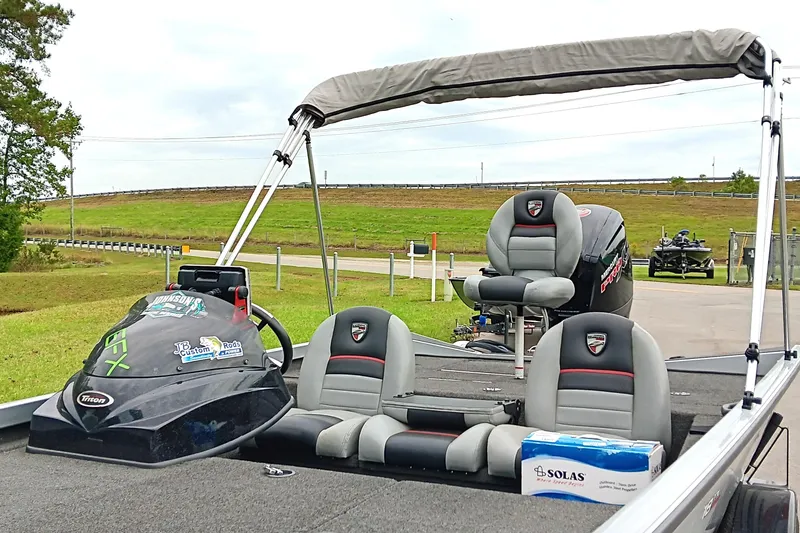 Slide: The Image of 2017 Triton 18 C TX boat with seating and canopy, parked near a grassy area. - 10