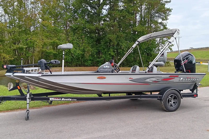 Slide: The Image of 2017 Triton 18 C TX boat on trailer, parked near trees and grass. - 3