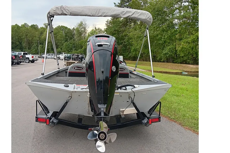 Slide: The Image of 2017 Triton 18 C TX boat with outboard motor, parked on a road near greenery. - 8