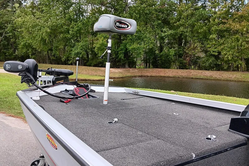 Slide: The Image of 2017 Triton 18 C TX boat with fishing equipment by a serene lake. - 9