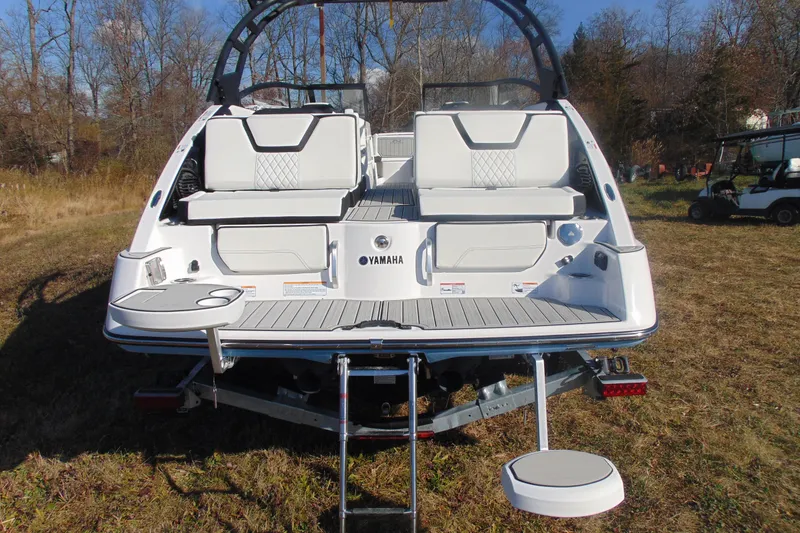 Slide: The Image of 2026 Yamaha Boats 252SD rear view with seating and swim platform in a grassy area. - 6