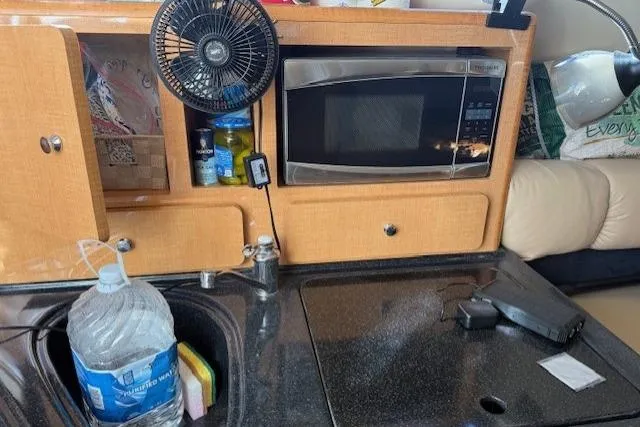 Slide: The Image of Compact kitchen area in a 2016 Glastron GS 289 boat with microwave and sink. - 22