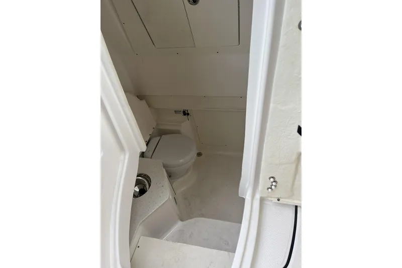 Slide: The Image of 2023 Robalo R302 Center Console boat interior with compact marine toilet. - 16