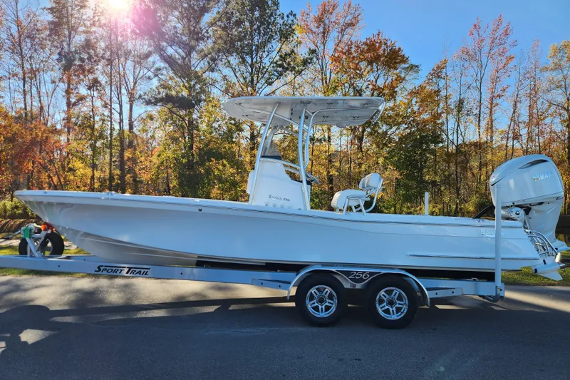 The Image of 2026 BlackJack 256 Bay boat on trailer, surrounded by autumn trees. - 0