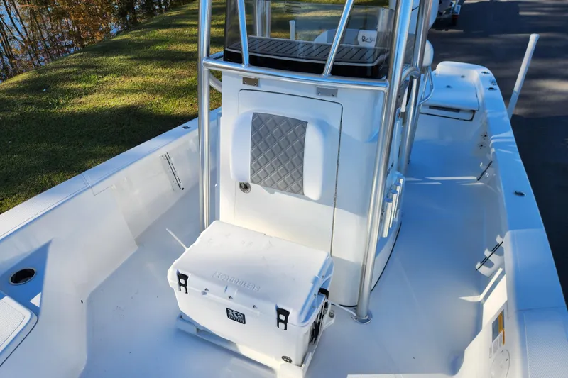 Slide: The Image of 2026 BlackJack 256 Bay boat interior with cooler and seating, docked near grassy area. - 11