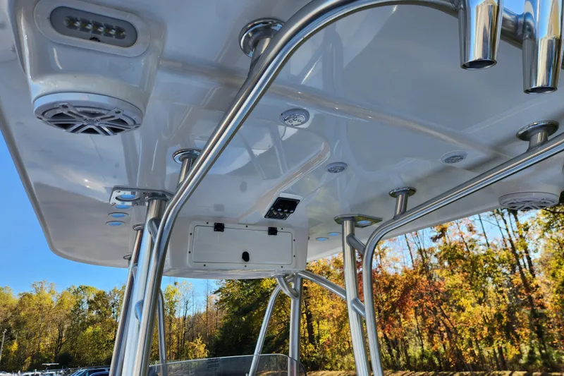 Slide: The Image of T-top of 2026 BlackJack 256 Bay boat with speakers and rod holders, set against autumn trees. - 13