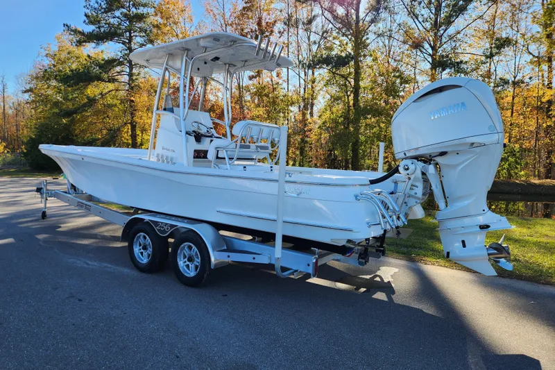 Slide: The Image of 2026 BlackJack 256 Bay boat on trailer, parked on a scenic road. - 2