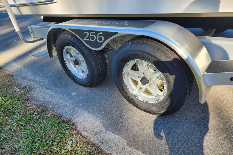 Slide: The Image of Trailer wheels of a 2026 BlackJack 256 Bay boat on pavement. - 7