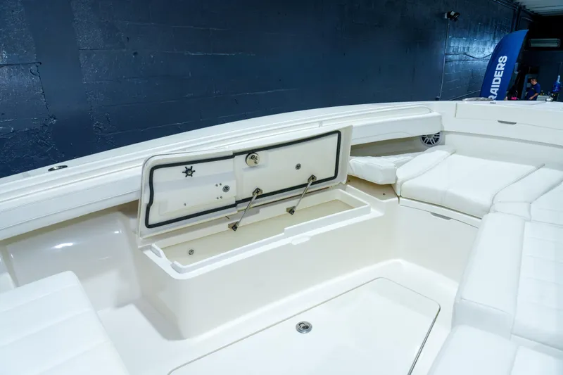Slide: The Image of 2023 Regulator 28 boat interior with white cushioned seating and storage compartments. - 26
