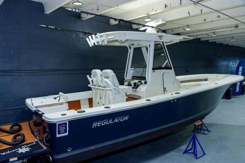 Slide: The Image of 2023 Regulator 28 boat in a showroom, elevated on stands, with a sleek blue hull. - 3