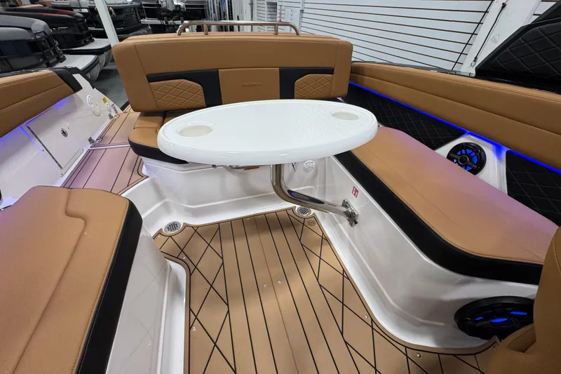 Slide: The Image of 2026 Chaparral 6 SSX boat interior with tan seating, white table, and blue accent lighting. - 17