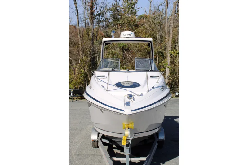 Slide: The Image of 2019 Regal 28 Express boat on trailer, surrounded by trees. - 2