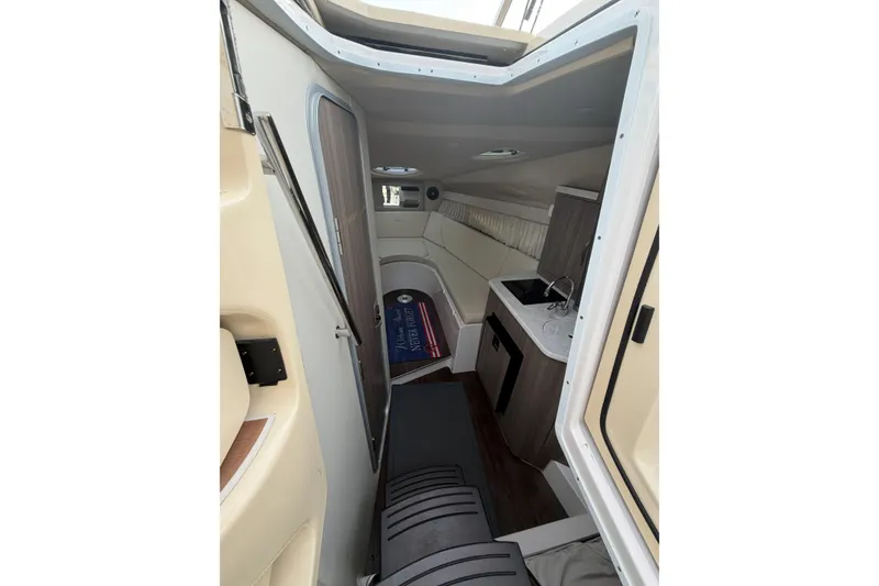 Slide: The Image of Interior of a 2019 Regal 28 Express boat, featuring a compact kitchen and seating area. - 20