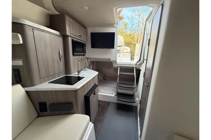 Slide: The Image of 2019 Regal 28 Express boat interior with kitchenette, TV, and stairs leading outside. - 22