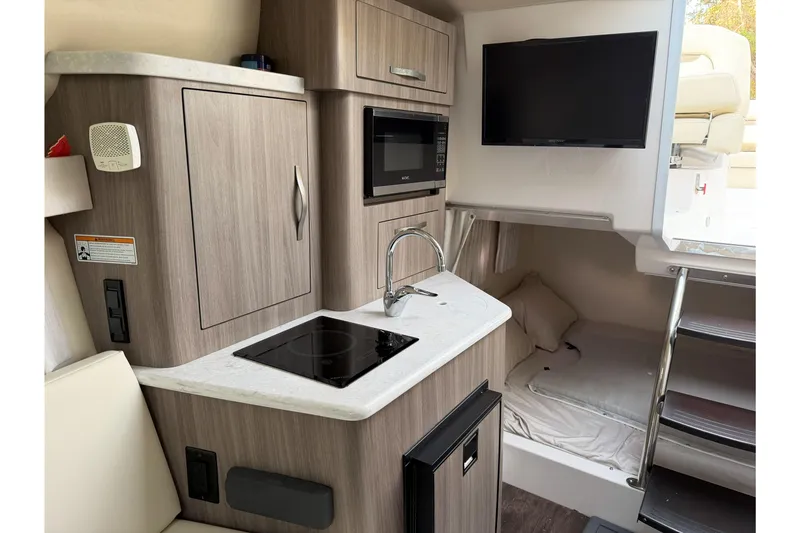 Slide: The Image of 2019 Regal 28 Express boat interior with kitchenette, TV, and sleeping area. - 24