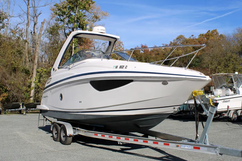 Slide: The Image of 2019 Regal 28 Express boat on trailer, parked outdoors with trees in background. - 3