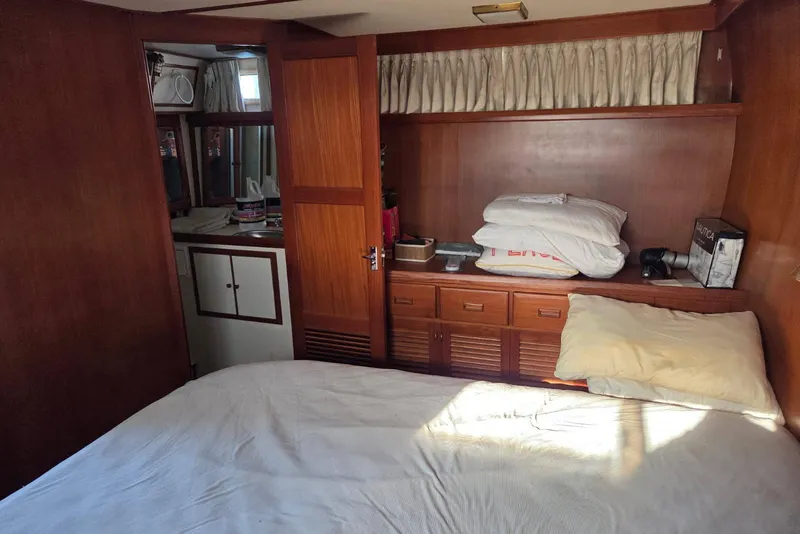 Slide: The Image of 1988 Novamarine 36 Heritage East Trawler cabin with bed, wooden cabinets, and porthole. - 10