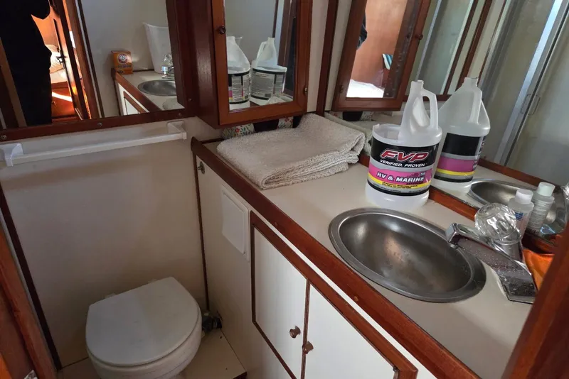 Slide: The Image of 1988 Novamarine 36 Heritage East Trawler bathroom with sink, mirror, and cleaning supplies. - 14