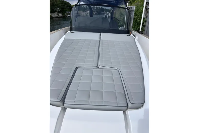 Slide: The Image of 2024 Pardo Yachts P38 with sleek gray cushioned deck, docked by lush greenery. - 12